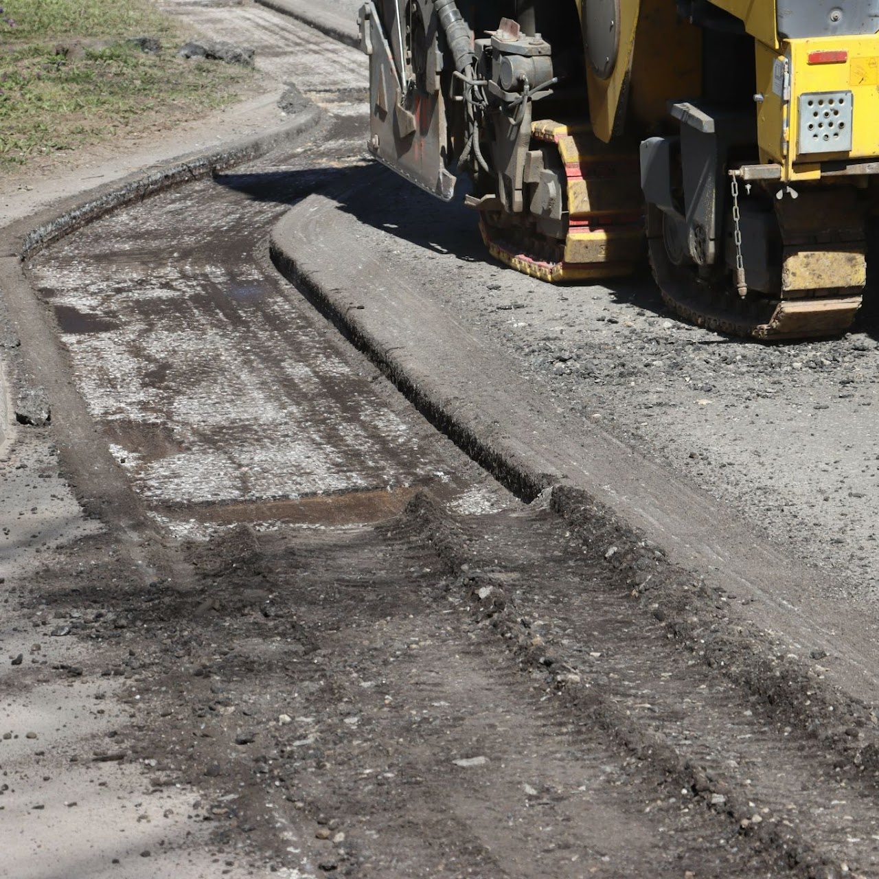 A heavy duty machine performing asphalt milling and resurfacing on a roadway, with dug-up asphalt visible on the side, showcasing Morris Town Paving's roadway paving services in Morris County, NJ.