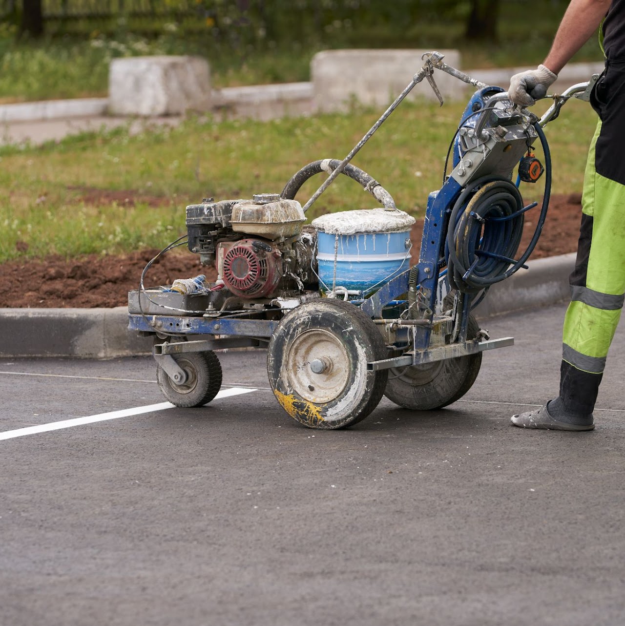 A worker using a machine to draw lines in a parking lot in a recent project, highlighting Morris Town Paving's parking lot paving and maintenance services for a client in Morris County, NJ