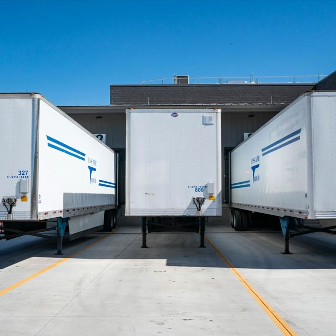 A commercial loading dock area featuring Morristown Paving's asphalt paving work in Morris County, NJ. Three white semi-trailers are parked at loading bays, showcasing the smooth, durable concrete surface and clear line striping essential for industrial facilities.