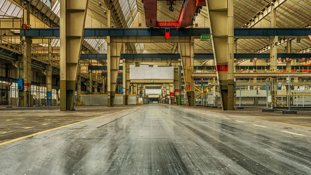 An expansive industrial warehouse facility showcasing Morristown Paving's commercial asphalt work in Morris County, NJ. The smooth, durable indoor concrete flooring extends through a large covered space with structural columns and overhead mechanical systems, demonstrating the company's capability in large-scale industrial paving projects.