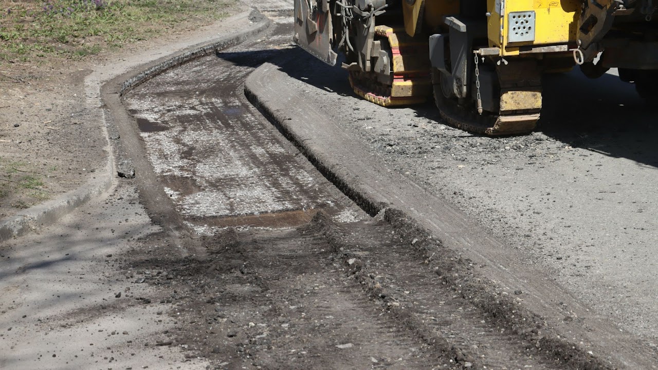 A machine performing asphalt milling and resurfacing on a roadway, with dug-up asphalt visible on the side, showcasing Morris Town Paving's roadway paving services in Morris County, NJ.