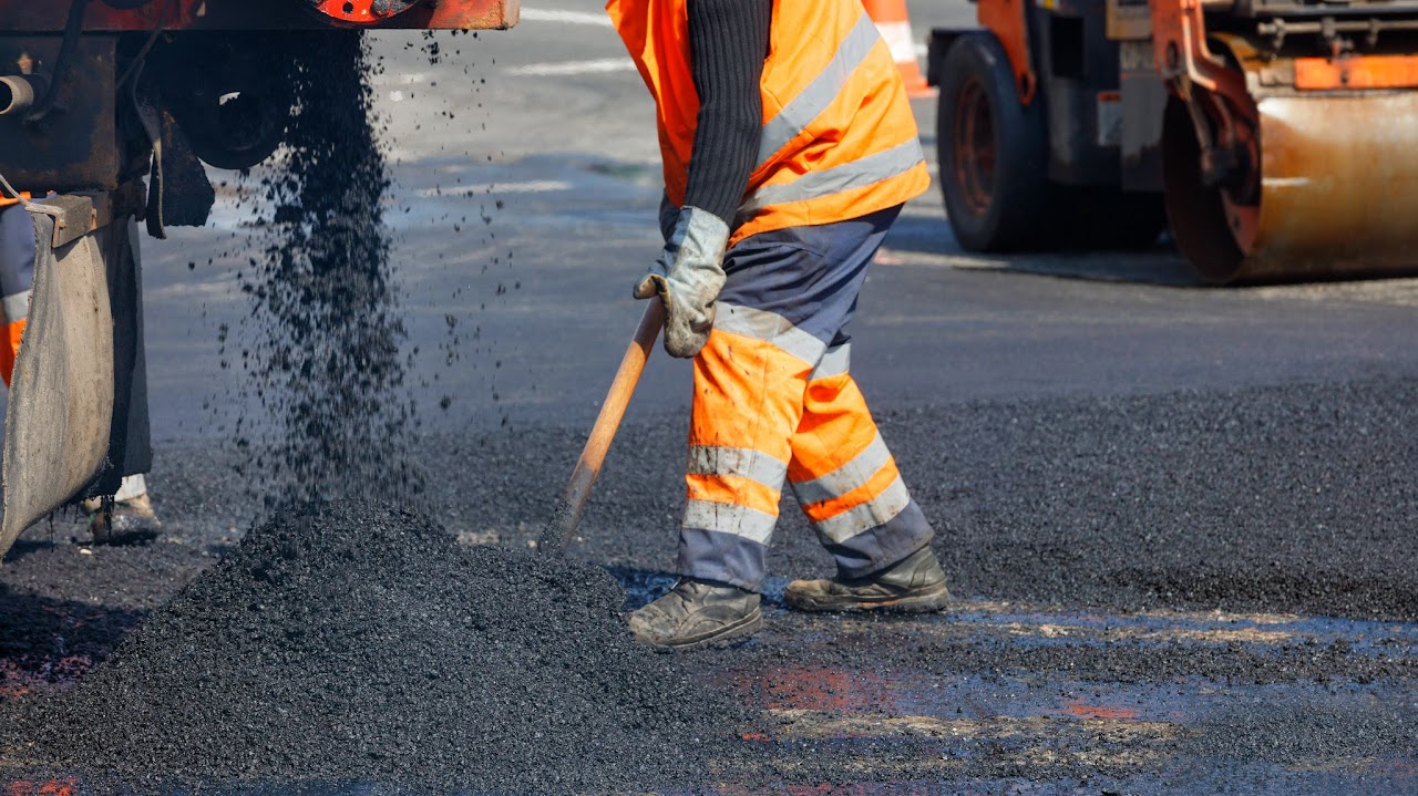 A worker in high-visibility gear spreading asphalt during roadway paving services, highlighting Morris Town Paving's professional road construction expertise in Morris County, NJ.